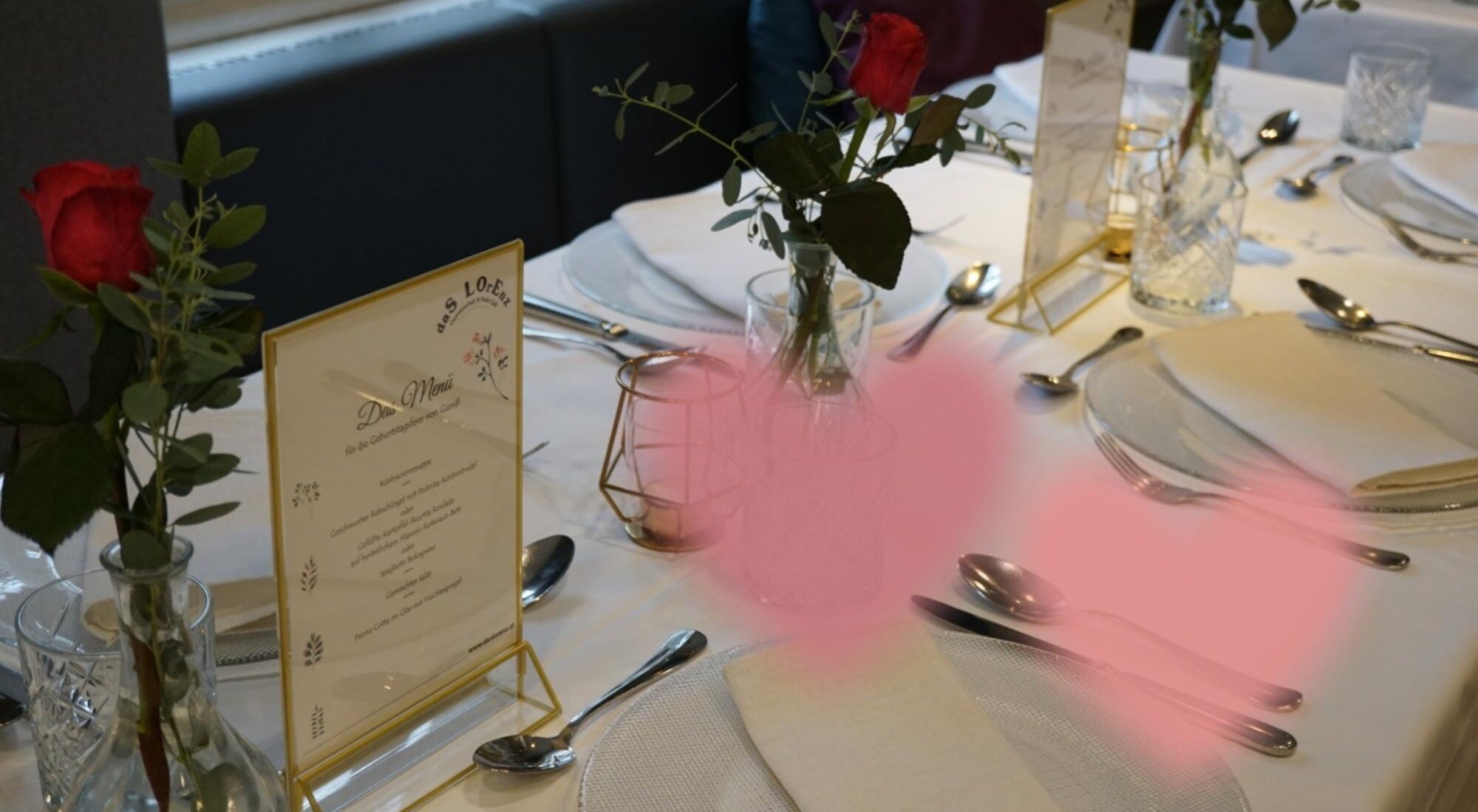 Ein Foto von einem festlich gedeckten Tisch im Lorenz mit roten Rosen als Dekoration.